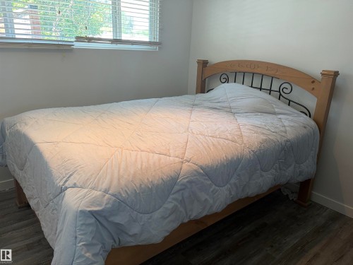 Room featuring wood-finish flooring, a window with horizontal blinds, and light-toned walls - 15922 92 Avenue, Edmonton, AB 