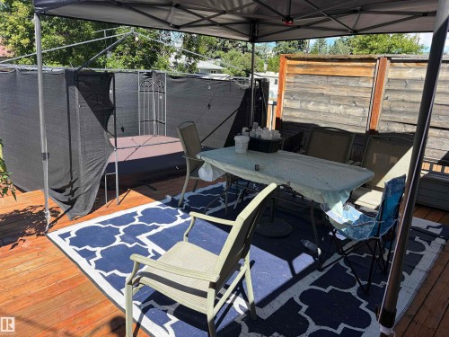 Expansive wood deck featuring a covered outdoor area, a built-in spa, and a privacy screen - 15922 92 Avenue, Edmonton, AB 