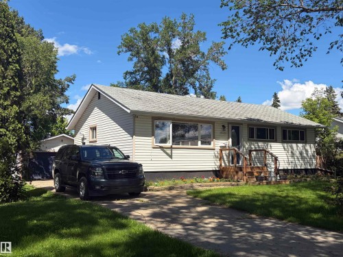 Single-story residence featuring light-colored siding, a pitched roof with grey shingles, and a front entry with wooden steps and railing - 15922 92 Avenue, Edmonton, AB 
