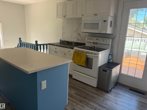 Kitchen featuring white cabinetry, dark stone countertops, and a white tile backsplash - 15922 92 Avenue, Edmonton, AB 