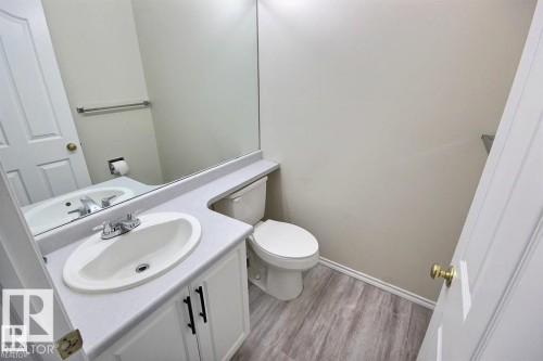 Vanity with an integrated sink, white cabinetry with black hardware, and a large wall-mounted mirror - 9457 156 Street, Edmonton, AB 