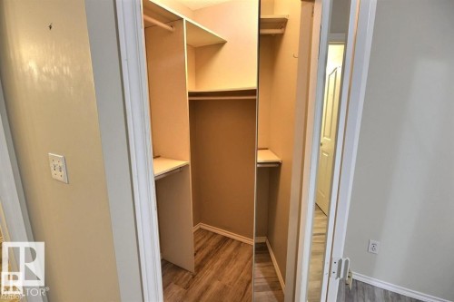 Walk-in closet featuring built-in shelving, hanging rods, and wood-finish flooring - 9457 156 Street, Edmonton, AB 
