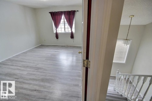 Spacious room with wood-finish flooring and multiple windows, providing natural light - 9457 156 Street, Edmonton, AB 