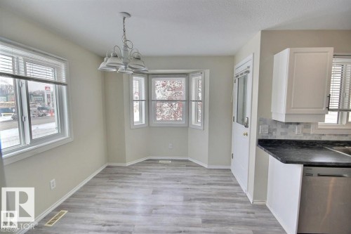 Bright dining area featuring wood-finish flooring, a contemporary chandelier, and a bay window - 9457 156 Street, Edmonton, AB 