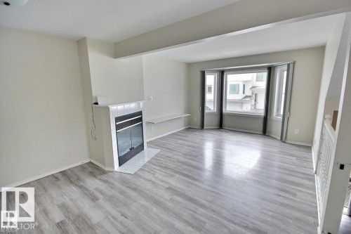 Living area featuring a bay window, wood-finish flooring, a fireplace with a tiled hearth, and a built-in shelf - 9457 156 Street, Edmonton, AB 
