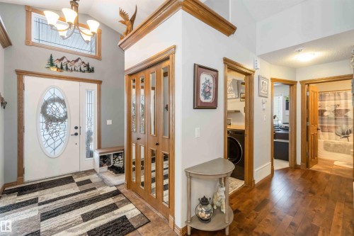 Welcoming entryway featuring a decorative front door with an oval glass insert, a transom window, and hardwood flooring - 61 Linkside Blvd, Spruce Grove, AB 