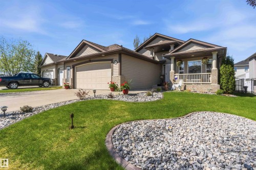 Front exterior featuring a covered porch with column supports, a two-car garage, and an additional single-car garage - 61 Linkside Blvd, Spruce Grove, AB 