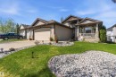 Front exterior featuring a covered porch with column supports, a two-car garage, and an additional single-car garage - 61 Linkside Blvd, Spruce Grove, AB 