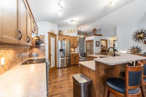 The kitchen features wood cabinetry, a tiled backsplash, and stainless steel appliances - 61 Linkside Blvd, Spruce Grove, AB 