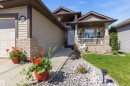 Front exterior featuring a covered porch with decorative columns, brick detailing, and horizontal siding - 61 Linkside Blvd, Spruce Grove, AB 