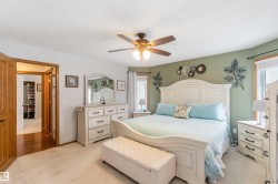 The bedroom features light-colored carpeting, a ceiling fan, and a light green accent wall - 