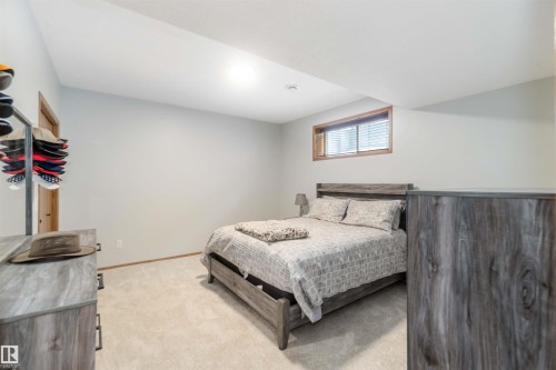 The property features a bedroom with neutral carpeting, light-colored walls, and a window with blinds - 61 Linkside Blvd, Spruce Grove, AB 