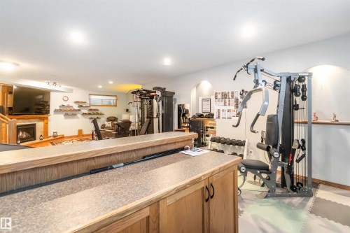 The property features a finished entertainment space with a fireplace, recessed lighting, and a window - 61 Linkside Blvd, Spruce Grove, AB 