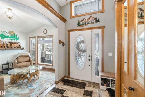 The entrance features a white door with an oval-shaped leaded glass insert, complemented by a sidelight with a similar design - 61 Linkside Blvd, Spruce Grove, AB 