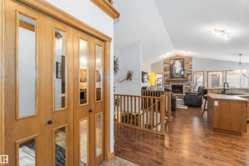 The property offers a welcoming entrance with wooden bifold doors, leading into an open living space featuring hardwood floors and a vaulted ceiling - 61 Linkside Blvd, Spruce Grove, AB 