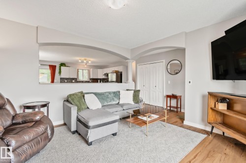 Living area featuring wood-finish flooring, a patterned area rug, and light gray wall paint - 5161 54 Avenue, Redwater, AB - Indoor Photo Showing Living Room
