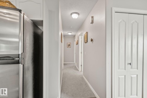 Hallway featuring light gray carpeting, white trim, and white paneled bi-fold doors - 5161 54 Avenue, Redwater, AB - Indoor Photo Showing Other Room