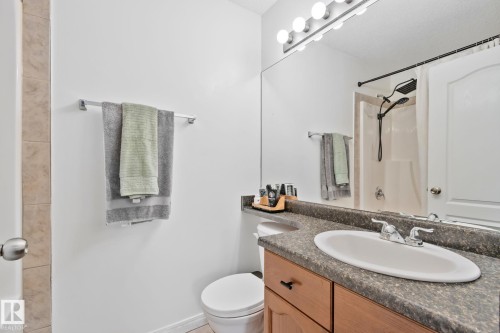 Bathroom featuring a wood-finish vanity with a dark speckled countertop, oval drop-in sink, and chrome faucet - 5161 54 Avenue, Redwater, AB - Indoor Photo Showing Bathroom