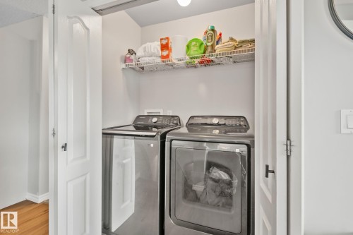 In-unit laundry closet featuring a stacked washer and dryer, wire shelving, and overhead lighting - 5161 54 Avenue, Redwater, AB - Indoor Photo Showing Laundry Room