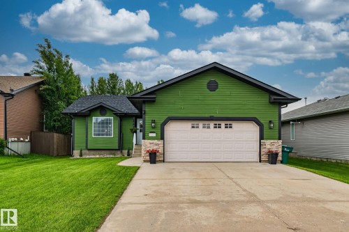 Contemporary exterior featuring green siding, black trim, and a prominent front-facing garage with a white door - 5161 54 Avenue, Redwater, AB - Outdoor