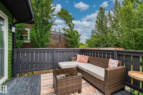 Spacious outdoor deck featuring dark-stained wood flooring and railing, a privacy fence, and mature perimeter trees - 5161 54 Avenue, Redwater, AB - Outdoor With Deck Patio Veranda With Exterior