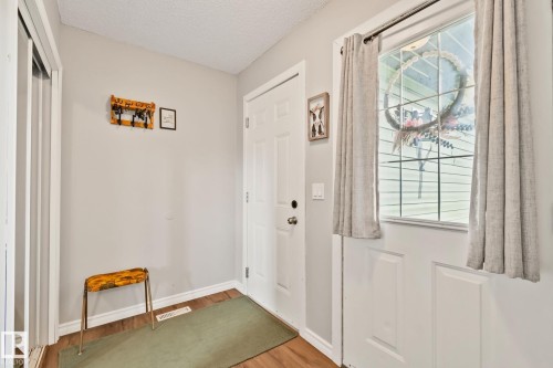 Entryway featuring wood-finish flooring, a white paneled door with a window, and a built-in closet with mirrored sliding doors - 5161 54 Avenue, Redwater, AB - Indoor Photo Showing Other Room