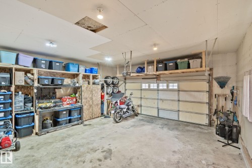 Attached garage featuring a concrete floor, overhead lighting, and extensive built-in shelving - 5161 54 Avenue, Redwater, AB - Indoor Photo Showing Garage