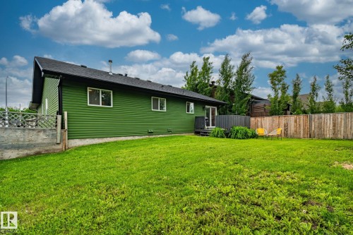 Expansive backyard featuring a lush lawn, solid wood privacy fencing, and a dark stained deck - 5161 54 Avenue, Redwater, AB - Outdoor