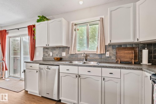 Kitchen featuring white cabinetry, a double basin stainless steel sink, and a stainless steel dishwasher - 5161 54 Avenue, Redwater, AB - Indoor Photo Showing Kitchen With Double Sink