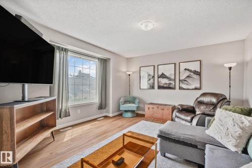 Spacious living area featuring wood-finish flooring, light grey wall paint, and a large window with white framing - 5161 54 Avenue, Redwater, AB - Indoor Photo Showing Living Room