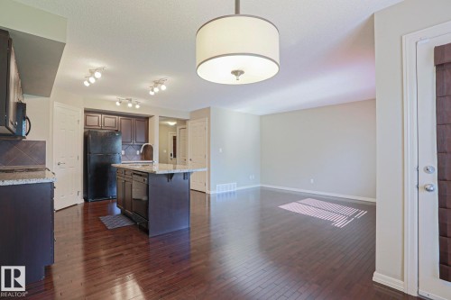 Open-concept living area with dark wood-finish flooring - 6215 60 Street, Beaumont, AB - Indoor Photo Showing Kitchen