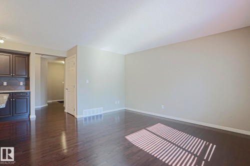 Spacious room featuring dark wood-finish flooring, light neutral-toned walls, and a recessed ceiling - 6215 60 Street, Beaumont, AB - Indoor