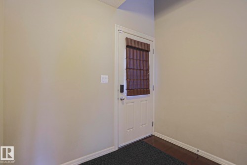 White panel entry door with a brown fabric window treatment and digital lock - 6215 60 Street, Beaumont, AB - Indoor Photo Showing Other Room