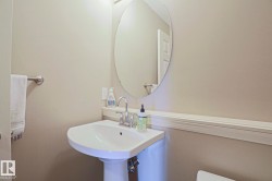 Pedestal sink with chrome faucet, circular mirror, and neutral wall tones - 