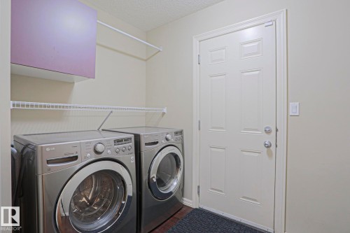 Dedicated laundry area featuring a built-in wire shelf, overhead storage cabinet, and a wall-mounted drying rod - 6215 60 Street, Beaumont, AB - Indoor Photo Showing Laundry Room