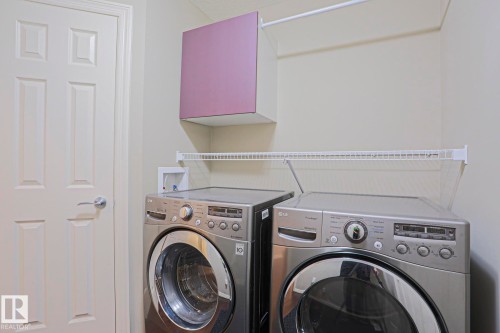 Dedicated laundry area featuring a white six-panel door, built-in wire shelving, and an overhead purple cabinet - 6215 60 Street, Beaumont, AB - Indoor Photo Showing Laundry Room
