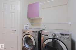 Dedicated laundry area featuring a white six-panel door, built-in wire shelving, and an overhead purple cabinet - 