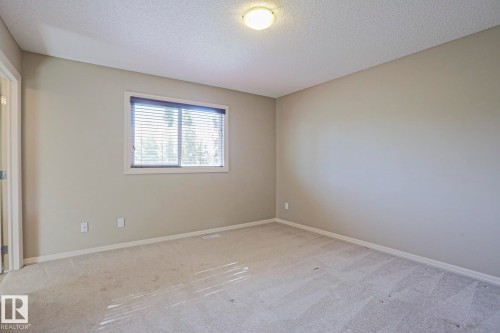Neutral-toned walls and light-colored carpeting with a window featuring horizontal blinds - 6215 60 Street, Beaumont, AB - Indoor Photo Showing Other Room