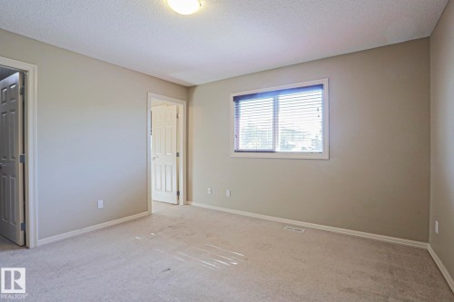 Carpeted room featuring a single window with blinds, a flush-mount ceiling light, and two interior panel doors - 6215 60 Street, Beaumont, AB - Indoor Photo Showing Other Room