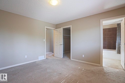 Carpeted room featuring neutral wall paint, white trim, and a flush mount ceiling light - 6215 60 Street, Beaumont, AB - Indoor