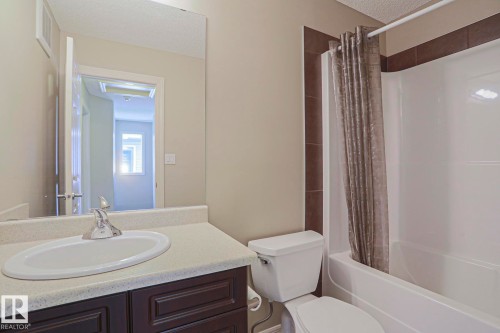 Bathroom featuring a vanity with an integrated sink, chrome faucet, and a dark wood-finish cabinet - 6215 60 Street, Beaumont, AB - Indoor Photo Showing Bathroom