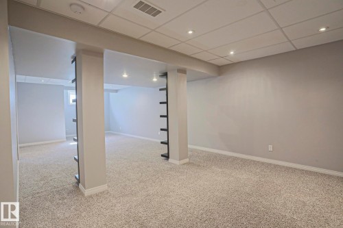Spacious room featuring light-toned carpet flooring and neutral wall color - 6215 60 Street, Beaumont, AB - Indoor