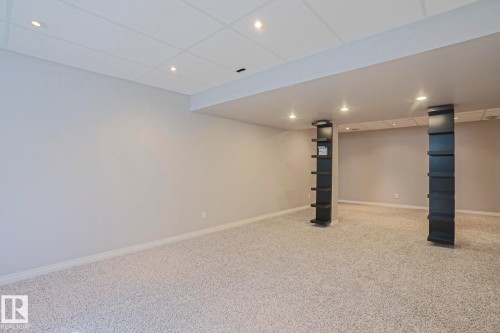 Spacious room featuring light-colored carpeting, neutral wall paint, and a drop ceiling with recessed lighting - 6215 60 Street, Beaumont, AB - Indoor