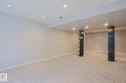Spacious room featuring light-colored carpeting, neutral wall paint, and a drop ceiling with recessed lighting - 