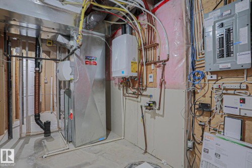 Utility area featuring a water heater, furnace, electrical panel, and exposed copper piping - 6215 60 Street, Beaumont, AB - Indoor Photo Showing Basement