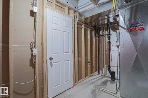 Unfinished interior space featuring exposed wood framing, a white paneled door, and concrete flooring - 6215 60 Street, Beaumont, AB - Indoor Photo Showing Basement