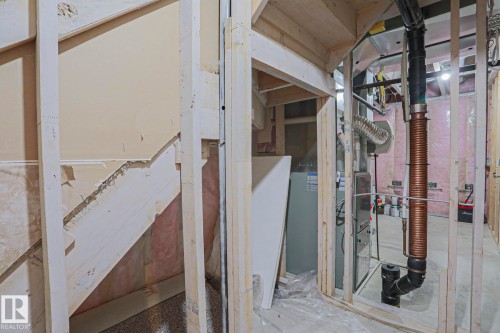 Unfinished interior space featuring exposed wood framing, visible utility lines, and a water heater - 6215 60 Street, Beaumont, AB - Indoor