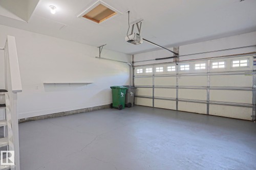 Spacious garage featuring a light gray concrete floor, white walls, and a white garage door with upper window panels - 6215 60 Street, Beaumont, AB - Indoor Photo Showing Garage