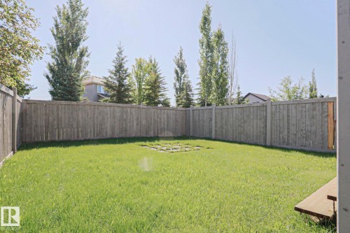Expansive backyard featuring a green lawn, full privacy fencing, and a central stone paver area - 6215 60 Street, Beaumont, AB - Outdoor