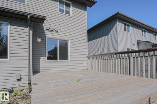 Expansive outdoor deck with a wooden railing and grey vinyl siding - 6215 60 Street, Beaumont, AB - Outdoor With Exterior